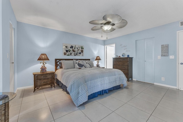 bedroom with ceiling fan, a closet, light tile patterned flooring, and a textured ceiling