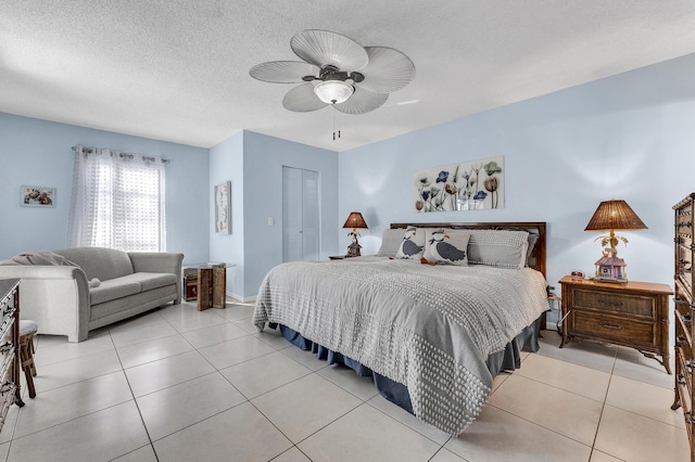 bedroom with ceiling fan, a textured ceiling, light tile patterned floors, and a closet