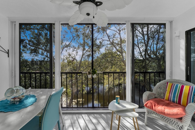 sunroom featuring ceiling fan, a healthy amount of sunlight, and a water view