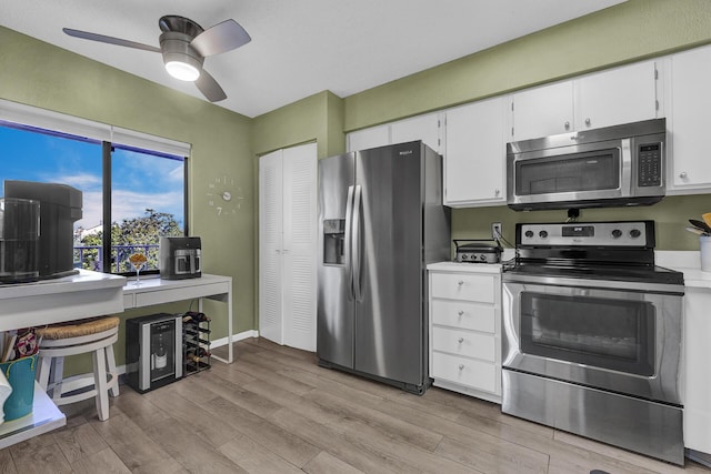 kitchen with light wood-type flooring, ceiling fan, appliances with stainless steel finishes, and white cabinets