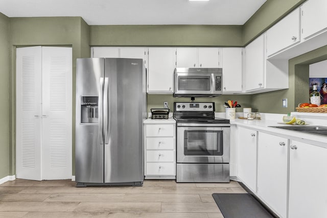 kitchen featuring stainless steel appliances, light hardwood / wood-style floors, white cabinetry, and sink