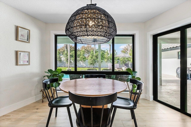 dining room with light hardwood / wood-style floors, a textured ceiling, and an inviting chandelier