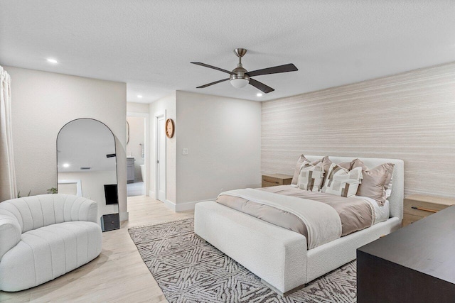 bedroom featuring ceiling fan, light hardwood / wood-style flooring, and a textured ceiling