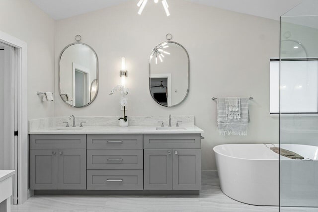 bathroom with vanity, a tub to relax in, and vaulted ceiling