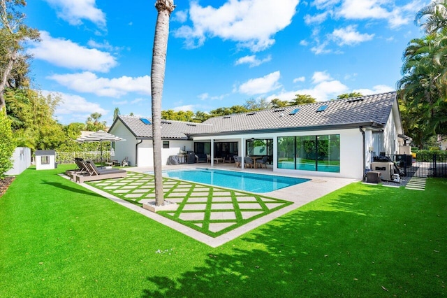 rear view of house featuring a fenced in pool, a patio area, and a lawn