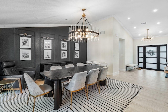 dining area with light hardwood / wood-style floors, lofted ceiling, ornamental molding, and an inviting chandelier