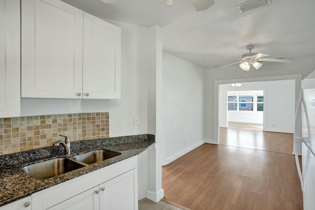 kitchen featuring white cabinetry, dark stone countertops, and sink