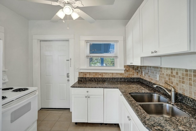 kitchen with white electric range oven, dark stone counters, sink, white cabinetry, and light tile patterned flooring