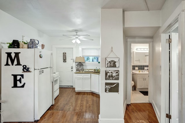 kitchen with white appliances, white cabinets, wood-type flooring, and decorative backsplash