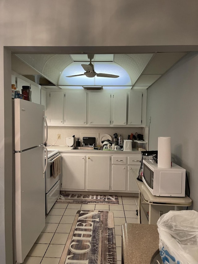 kitchen with white appliances, white cabinets, and light tile patterned floors