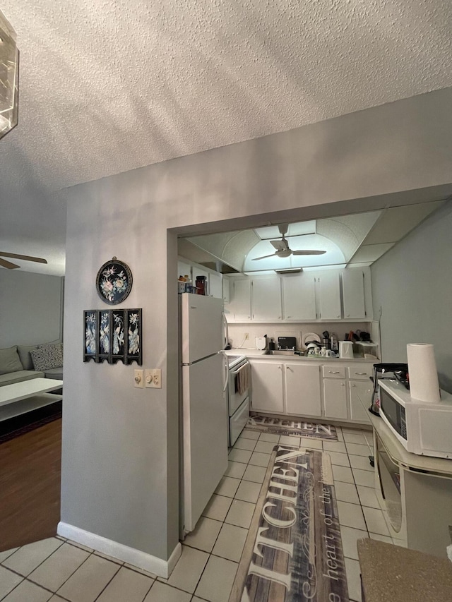 kitchen with white appliances, a textured ceiling, white cabinets, light tile patterned flooring, and ceiling fan