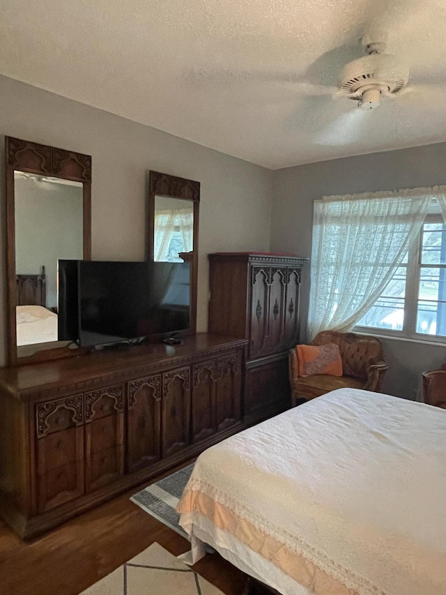 bedroom featuring hardwood / wood-style floors, a textured ceiling, ceiling fan, and multiple windows