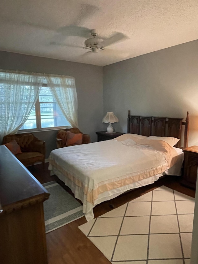 bedroom with ceiling fan, hardwood / wood-style floors, and a textured ceiling