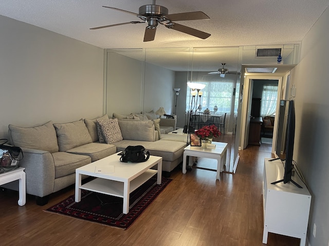 living room with a textured ceiling and dark hardwood / wood-style floors