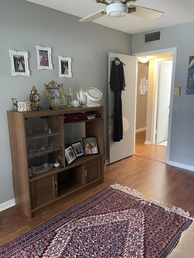 interior space with ceiling fan, a textured ceiling, and hardwood / wood-style flooring