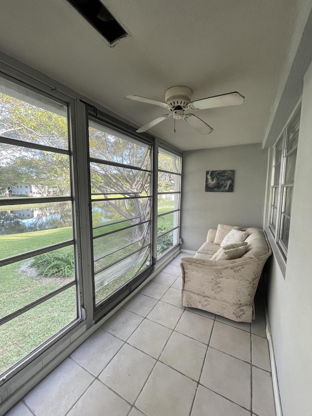 unfurnished sunroom with ceiling fan, plenty of natural light, and a water view