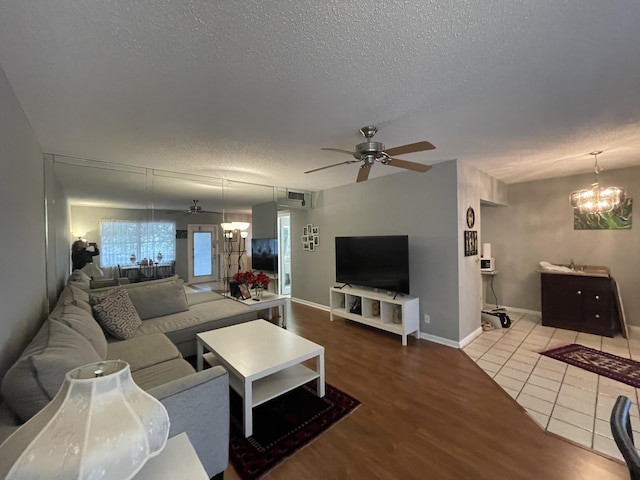 living room with ceiling fan with notable chandelier, a textured ceiling, and hardwood / wood-style flooring