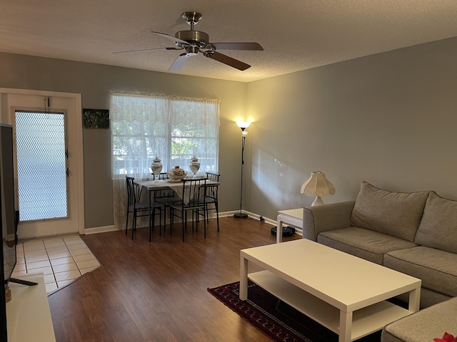 living room featuring dark hardwood / wood-style flooring, a textured ceiling, and ceiling fan