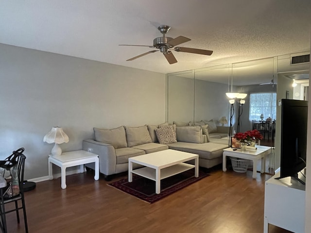 living room with dark hardwood / wood-style flooring, a textured ceiling, and ceiling fan