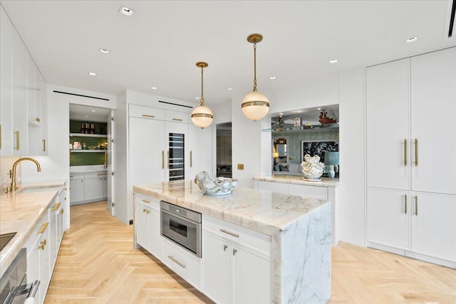 kitchen featuring white cabinetry, a center island, light parquet flooring, and decorative light fixtures