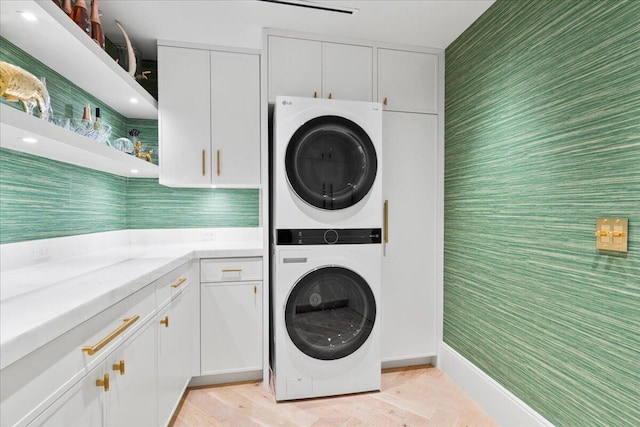 laundry area featuring cabinets and stacked washing maching and dryer