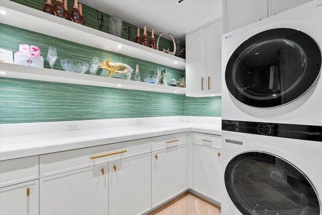 washroom with cabinets and stacked washing maching and dryer