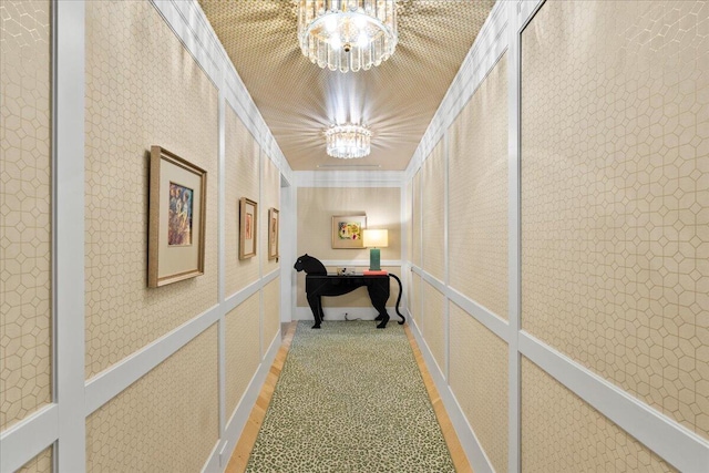 hall featuring crown molding, carpet floors, and a notable chandelier