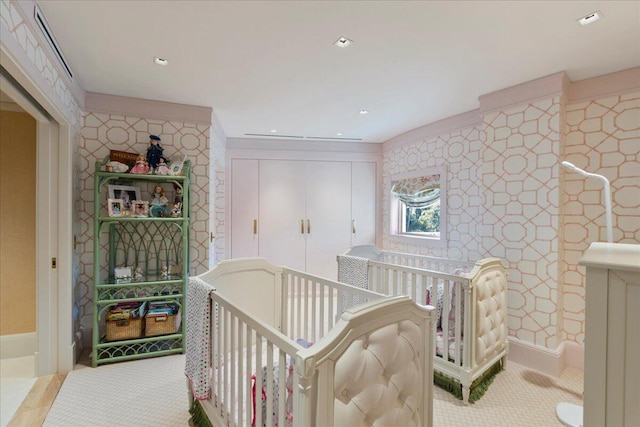 bedroom with light colored carpet and a nursery area