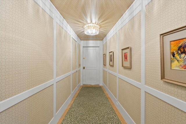 hallway featuring crown molding, carpet, and a chandelier