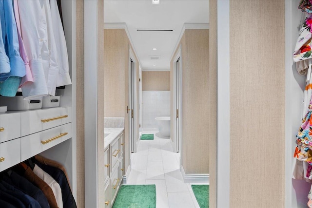 bathroom with tile patterned floors, ornamental molding, a washtub, vanity, and tile walls