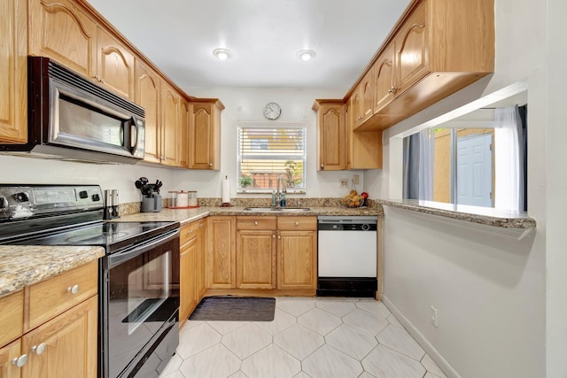 kitchen with black appliances, light stone counters, and sink