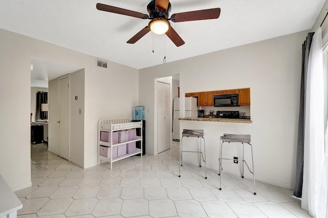 kitchen featuring kitchen peninsula, ceiling fan, a breakfast bar area, and black appliances