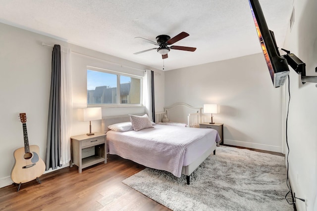 bedroom with ceiling fan, light hardwood / wood-style flooring, and a textured ceiling