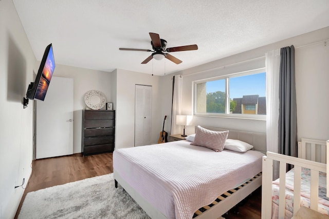 bedroom with ceiling fan, light hardwood / wood-style floors, a textured ceiling, and a closet