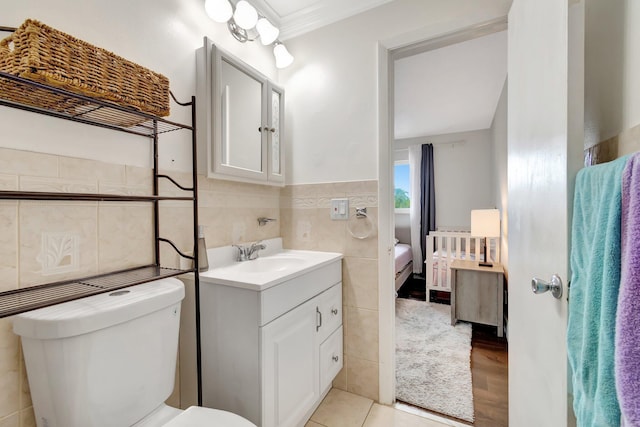 bathroom with vanity, toilet, tile walls, and crown molding