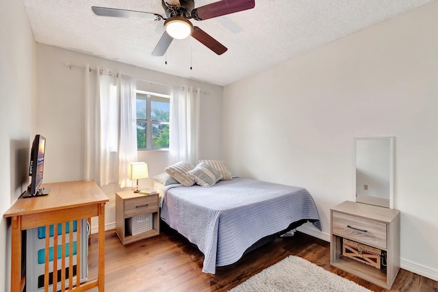 bedroom with a textured ceiling, ceiling fan, and dark hardwood / wood-style floors