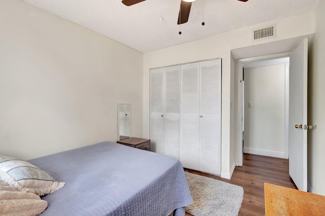 bedroom with a textured ceiling, a closet, ceiling fan, and dark wood-type flooring