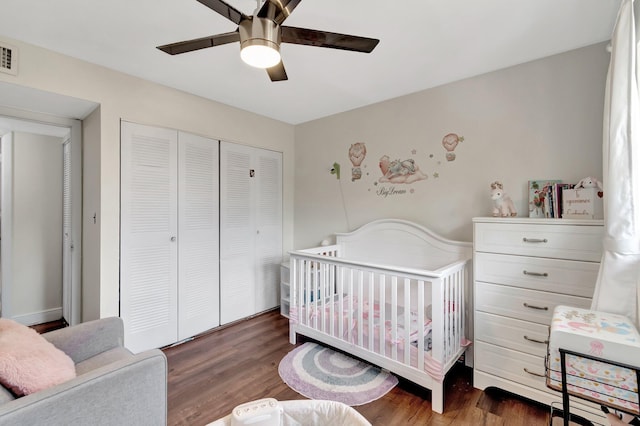 bedroom featuring dark hardwood / wood-style flooring, ceiling fan, a closet, and a nursery area