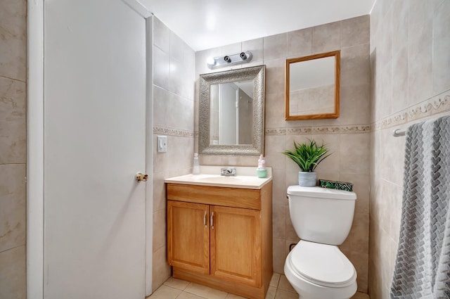 bathroom featuring tile patterned flooring, vanity, toilet, and tile walls