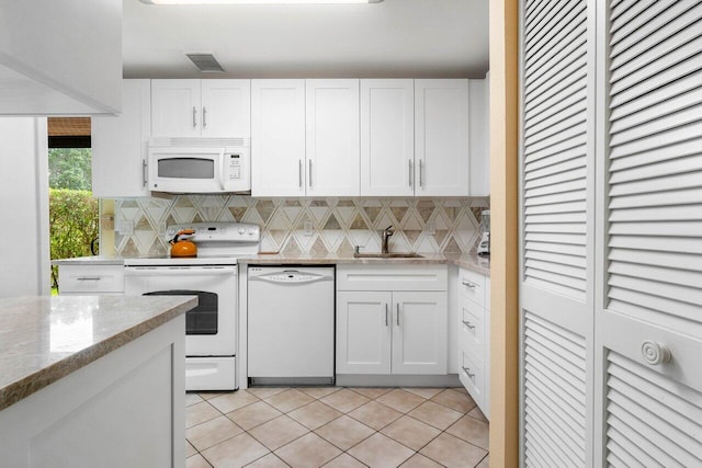 kitchen with light stone countertops, white appliances, sink, light tile patterned floors, and white cabinetry