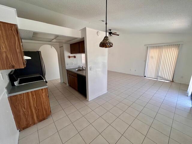 kitchen featuring ceiling fan, light tile patterned flooring, sink, and a textured ceiling