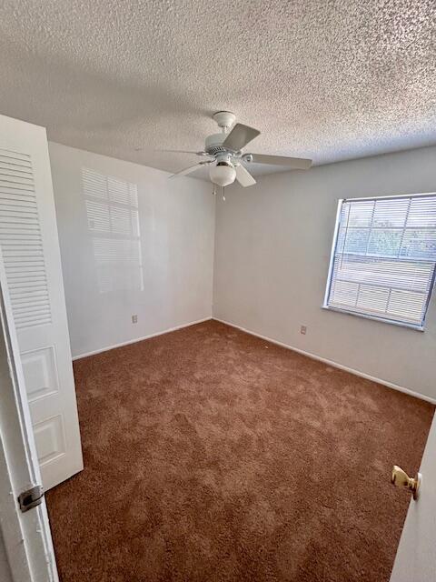 carpeted spare room with ceiling fan and a textured ceiling