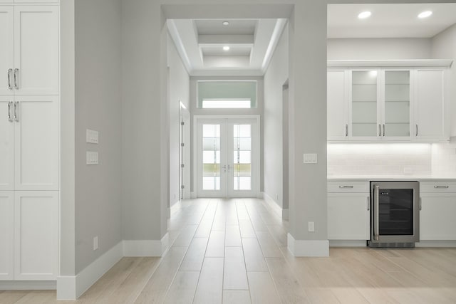 entryway featuring french doors, light wood-type flooring, a high ceiling, bar area, and wine cooler