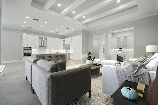 living room with ornamental molding, beverage cooler, sink, beamed ceiling, and light hardwood / wood-style floors