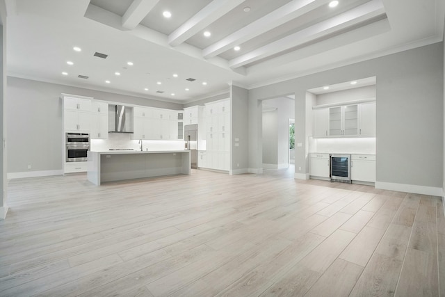 unfurnished living room featuring beam ceiling, light hardwood / wood-style floors, beverage cooler, and crown molding