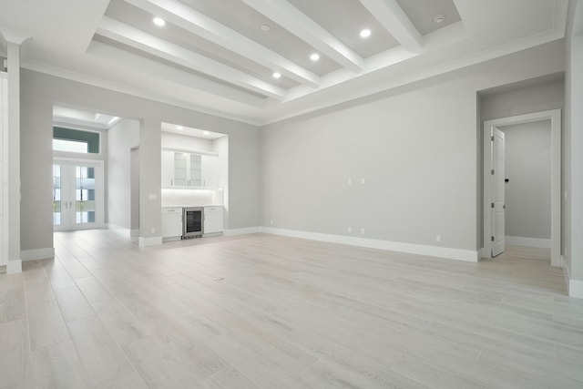 unfurnished living room with a tray ceiling, beverage cooler, and light hardwood / wood-style floors