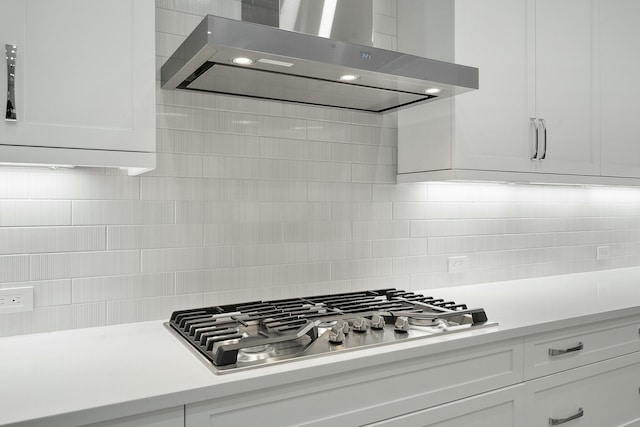 kitchen with tasteful backsplash, white cabinetry, exhaust hood, and stainless steel gas stovetop