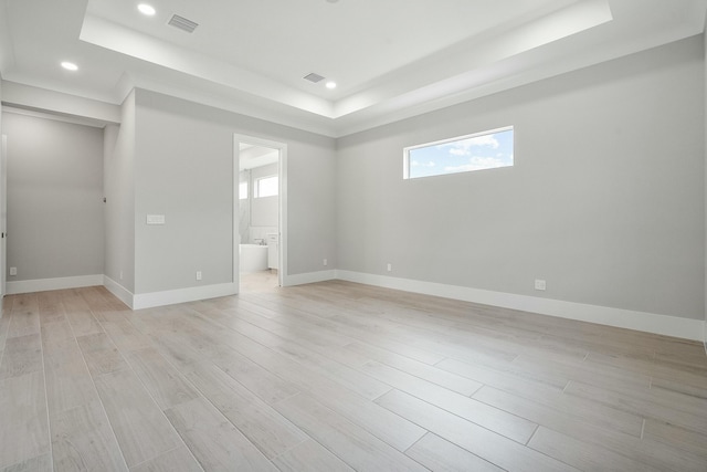 empty room with a tray ceiling and light hardwood / wood-style floors