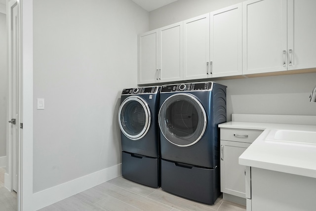 laundry area with washing machine and clothes dryer, sink, and cabinets