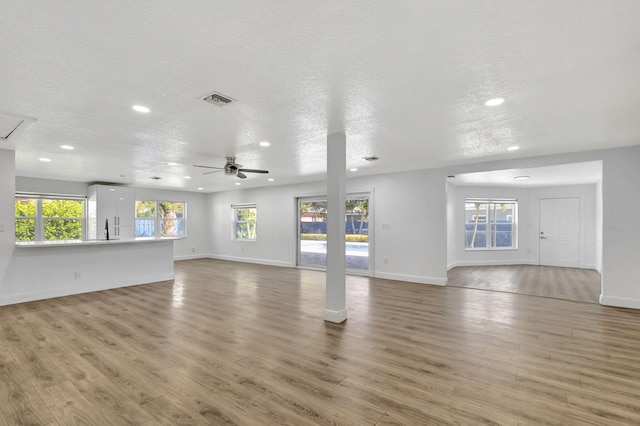 unfurnished living room featuring hardwood / wood-style floors, a textured ceiling, and ceiling fan